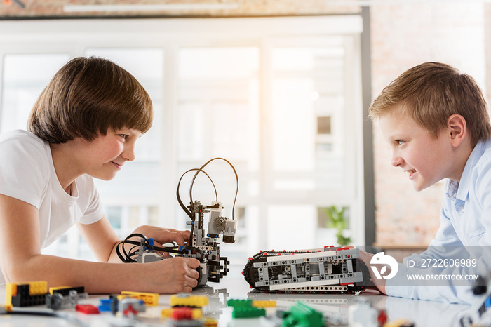 Cheerful male children playing with robotics