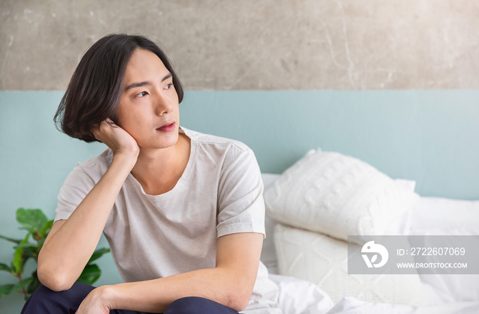 Portrait of young handsome asian man relax in bedroom. Smile happy asian boy in bed morning lifestyle with copy space. Japanese man facial skin care concept