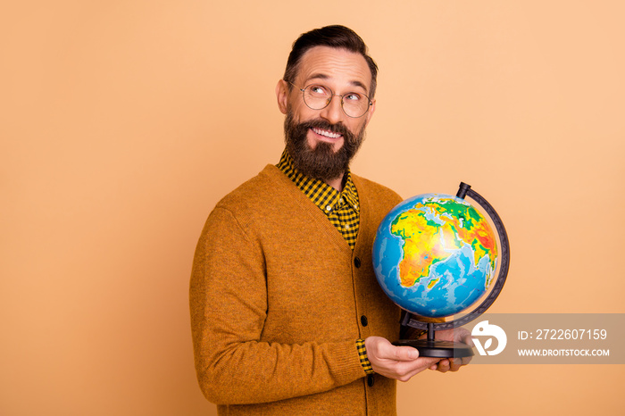 Photo of optimistic brown hair man hold globe look empty space wear spectacles brown sweater isolated on beige color background