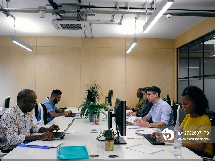 Office workers using computers in co-working office space