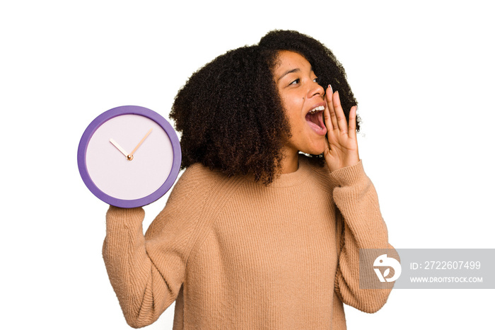 Young African American holding a clock isolated shouting and holding palm near opened mouth.