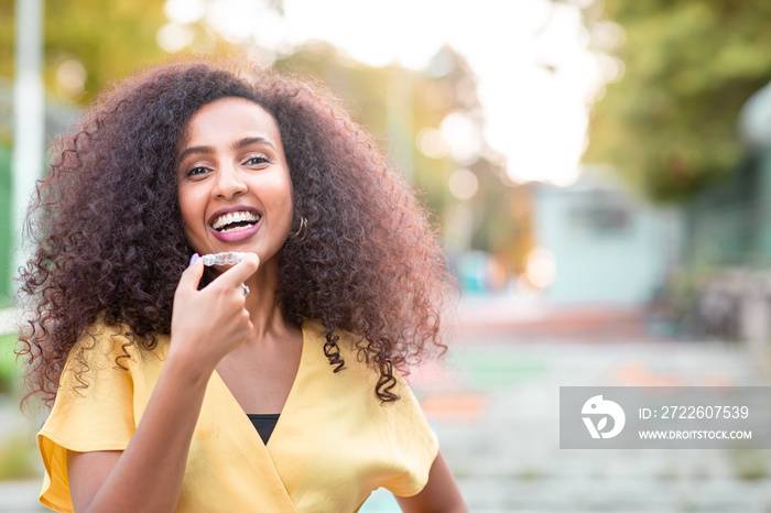 Beautiful smiling African black woman is holding invisaligner. Includes copy and text space.