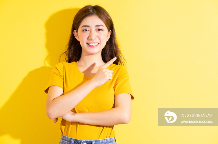 Young Asian girl posing on yellow background