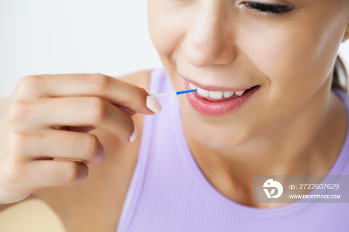 The woman uses brushes to clean the interdental spaces