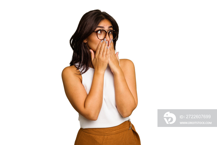 Young Indian woman isolated on green chroma background thoughtful looking to a copy space covering mouth with hand.