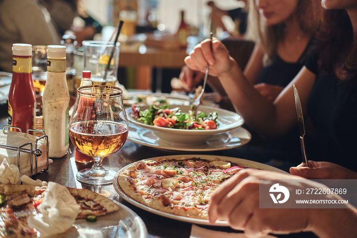 Pizza time. Young friends students eat pizza and salads in an outdoor caf during lunch break