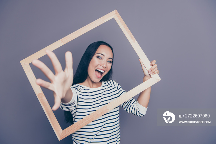 Close-up portrait of nice attractive funny cheerful cheery straight-haired lady in striped pullover holding frame hand going through isolated on gray pastel background