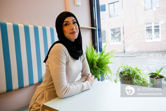 Young woman in hijab sitting in cafe