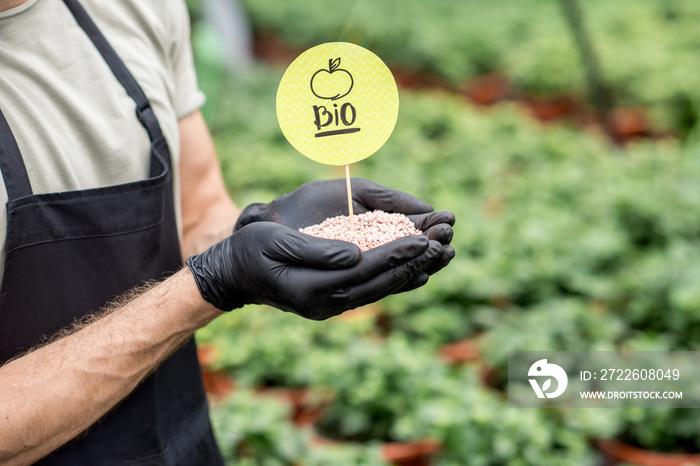 Farmer holding bio fertilizers with green plants on the background, close-up view