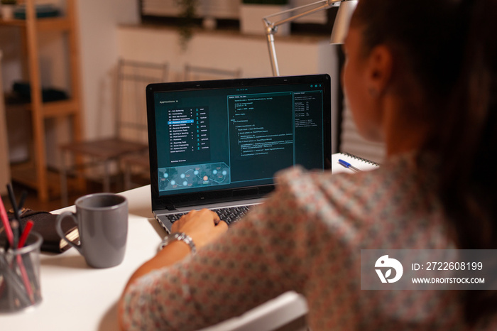 Female hacker sitting in front of computer and thinking how to fraud the government at night time. Programmer writing a dangerous malware for cyber attacks using performance laptop during midnight.