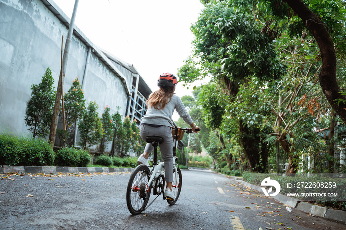 Asian young woman goes wearing a helmet to riding by folding bicycle on the road