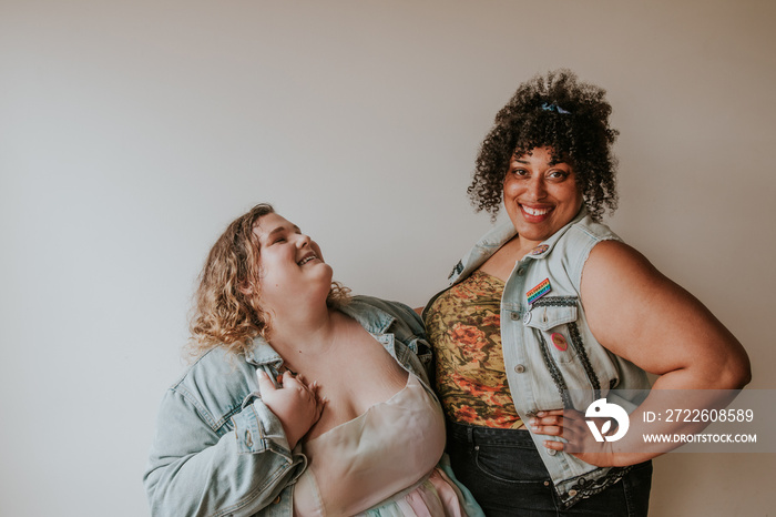 2 plus size friends stand together smiling