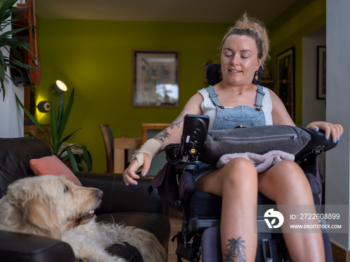 Woman in electric wheelchair with dog in living room