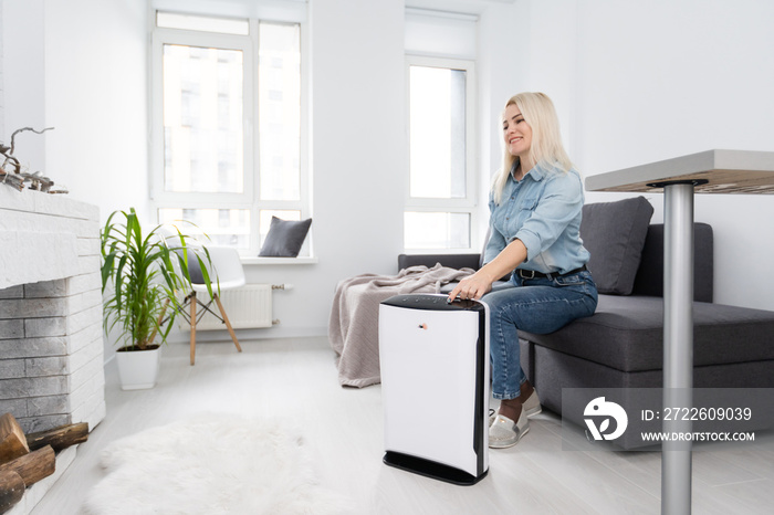 attractive woman with air purifier on windowsill