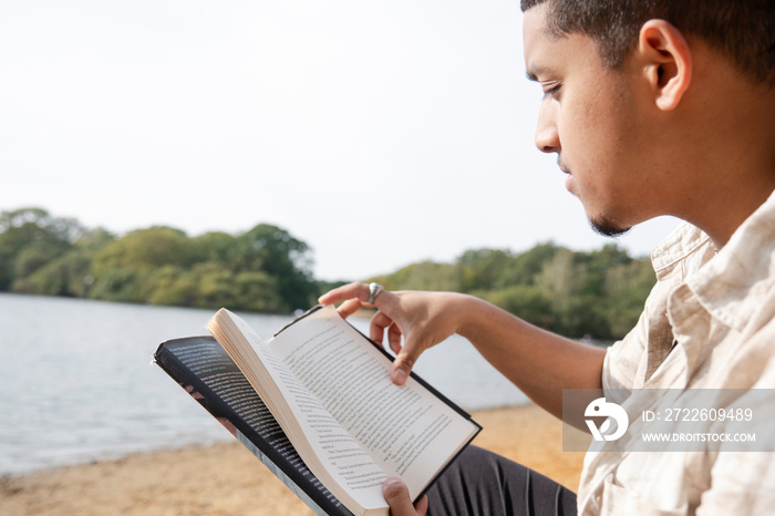 Close-up of man reading book on lakeshore