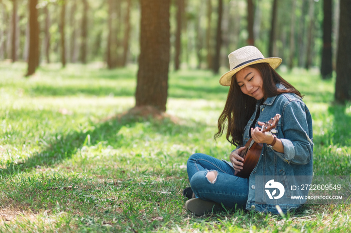 A beautiful asian woman sitting and playing ukulele in the park