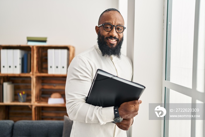 Young african american man psychologist holding binder at psychology center