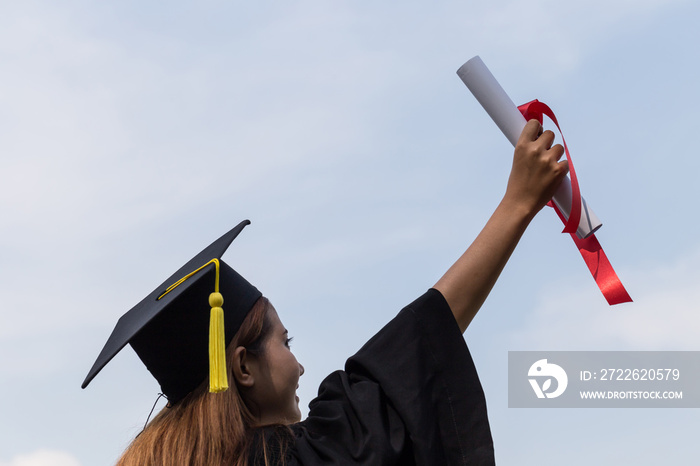 Back of view Graduate put her hands up and celebrating with certificate in her hand and feeling so proud and happiness in Commencement day,Education Success Concept