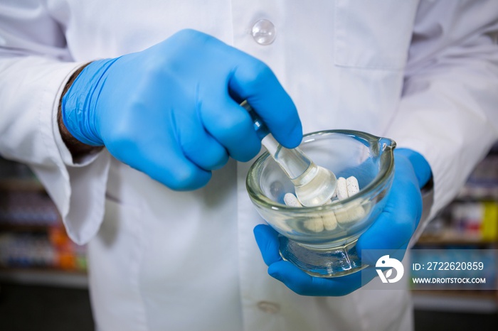 Pharmacist grinding medicine with mortar and pestle