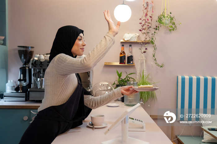 Young woman in hijab working in cafe