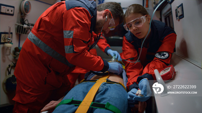 Mixed race doctors providing medical help of patient in ambulance car