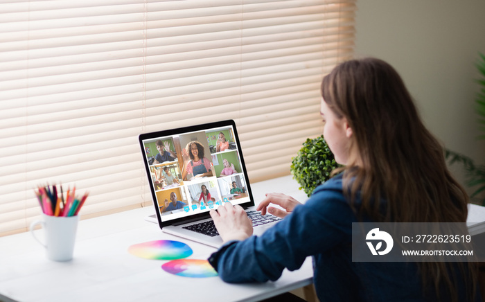 Caucasian woman using laptop for video call, with smiling diverse elementary school pupils on screen