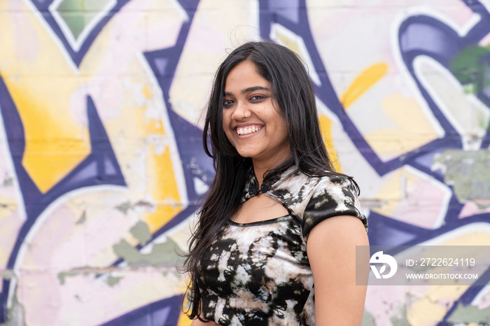 Portrait of young woman against graffiti wall