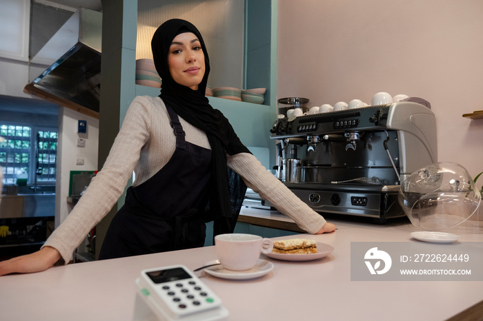 Portrait of young woman in hijab working in cafe