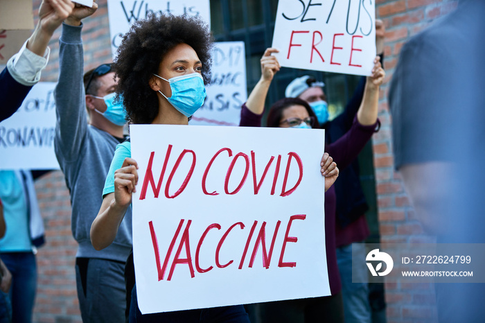 African American woman participating in anti vaccination protest on city streets.