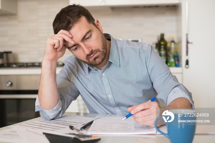 Frustrated man calculating bills and tax  expenses