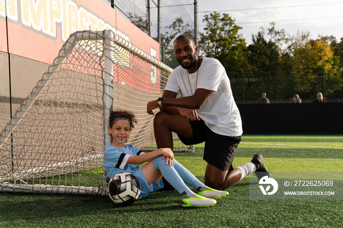 Portrait of coach and girl (6-7) by soccer goal