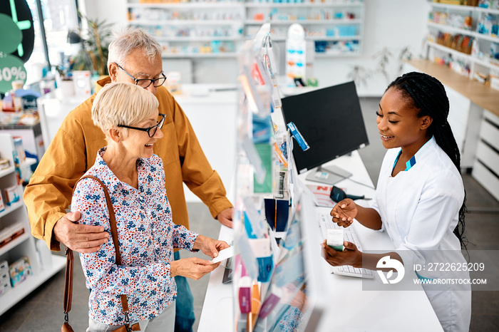 Happy senior couple buying prescription medicine in pharmacy.