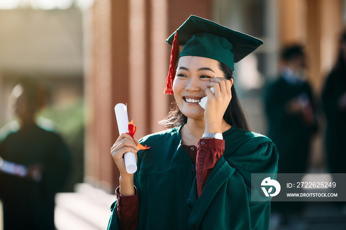 Happy Asian female student feeling emotional after receiving diploma on her graduation day.