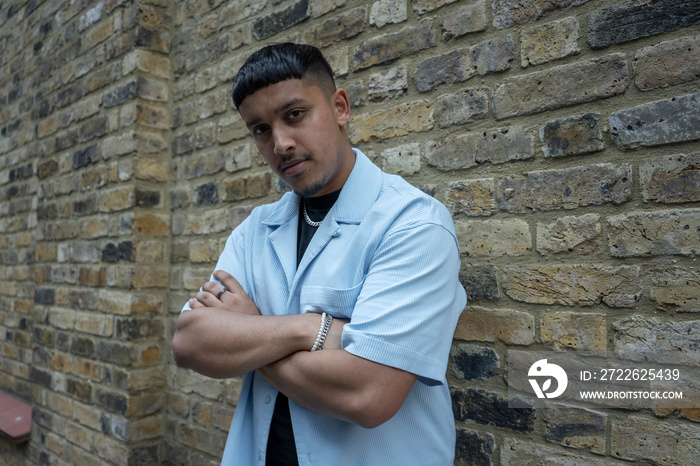 Man wearing shirt leaning on brick wall