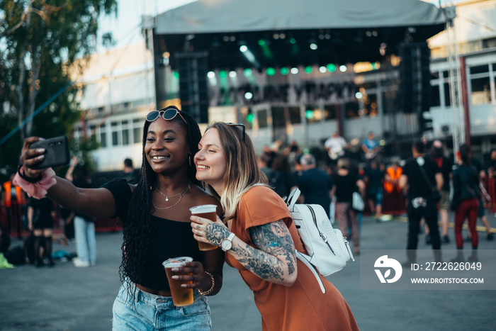 Two beautiful friends taking selfie with a smartphone on a music festival