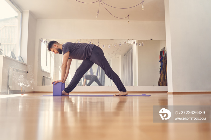 Handsome young man doing exercise with yoga blocks