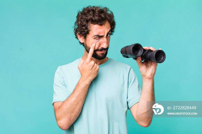 young adult hispanic crazy man with binoculars. searching concept