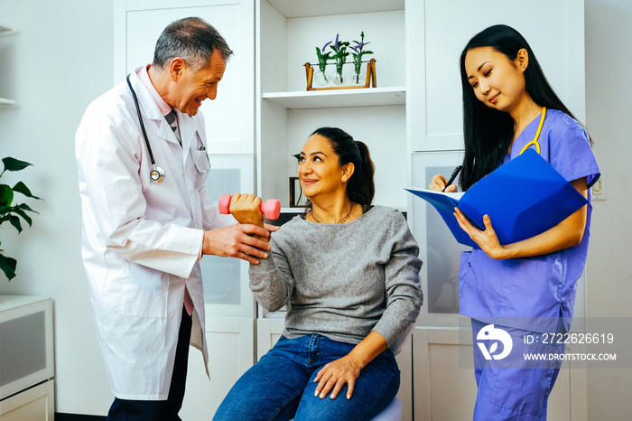 rehabilitation doctor physiotherapist physician and nurse practitioner helping patient lift dumbbell with one hand. Healthcare industry clinic