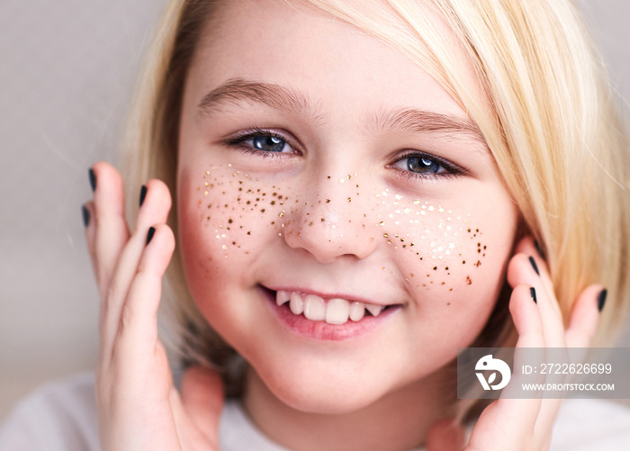 portrait of beautiful happy androgynous boy wearing tiara, golden freckles and nail polish, with long blonde hair