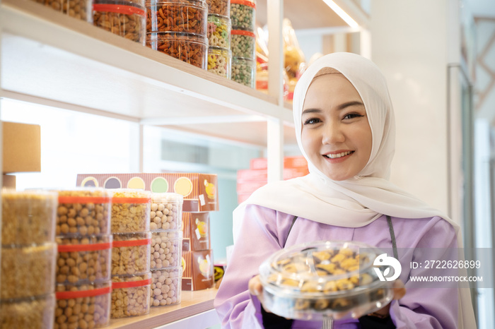 beautiful shop owner muslim woman holding some cake for eid mubarak in her store