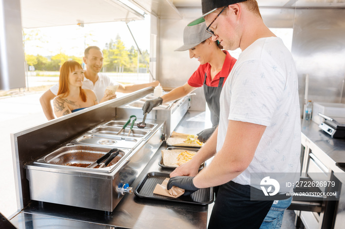 Young chefs in a food truck preparing Mexican food for their waiting customers