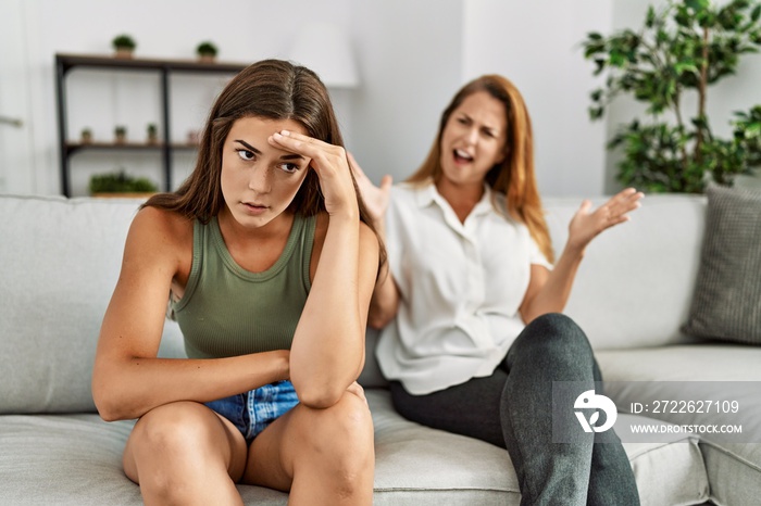 Mother and daughter unhappy arguing sitting on sofa at home