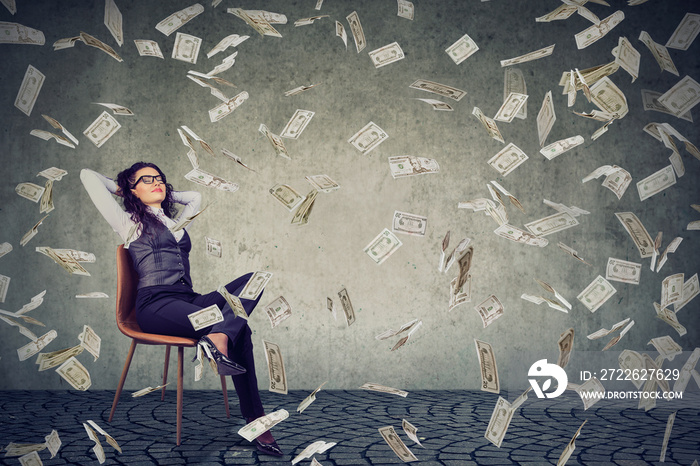 Successful woman sitting under money rain