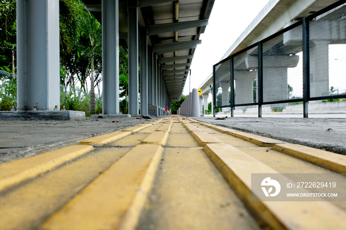 Yellow tactile paving guide path leading to a bus stand, installed to assist the visually impaired passengers and pedestrians.