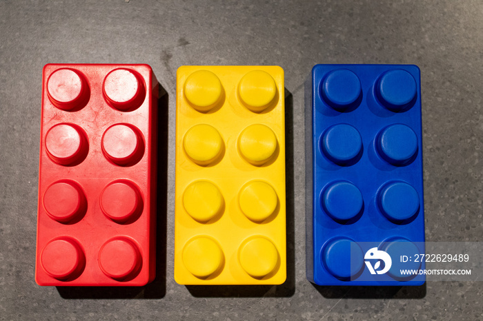 rectangular building blocks for children in yellow, blue and red colors. large format modular bricks lined up together. games for children with building elements