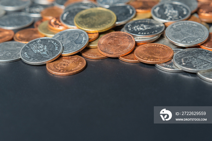 Heap coins on black table with space.