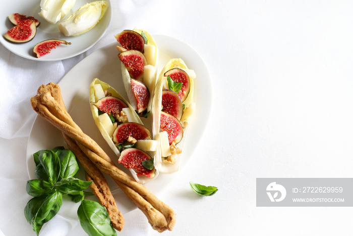 Insalata fresca con fichi, indivia, noci e formaggio su sfondo bianco. Vista dall’alto.