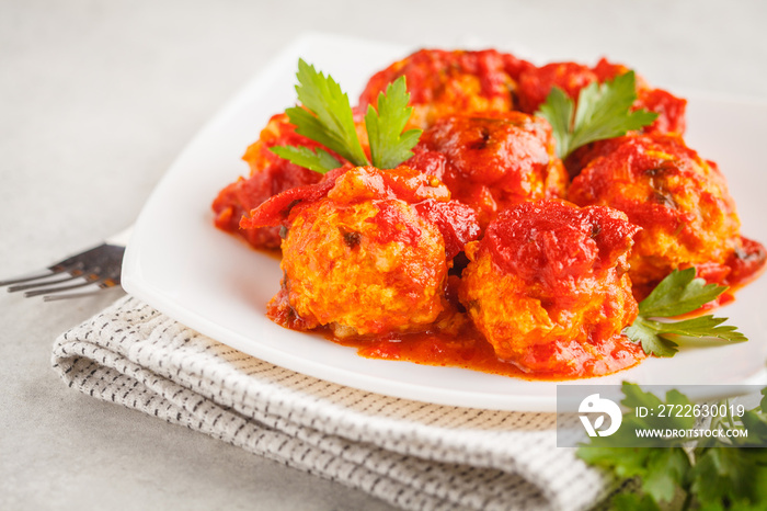 Chicken meatballs with tomato sauce in a white plate.