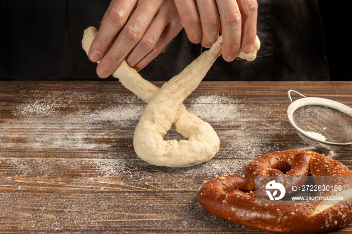 Step-by-step instructions for making pretzels. The cook rolls out the dough and rolls out the pretzel. Dark background.
