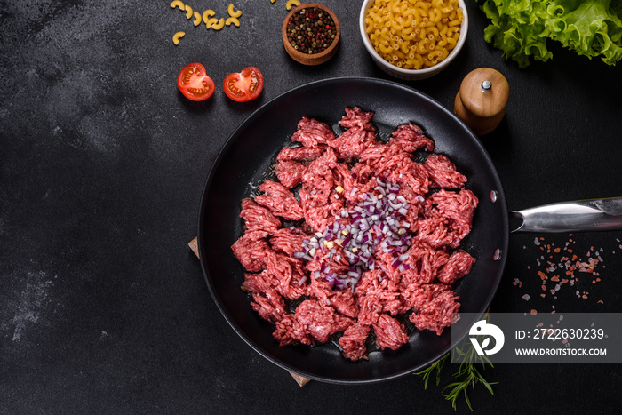 Fresh raw mince with spices and herbs on a dark concrete background